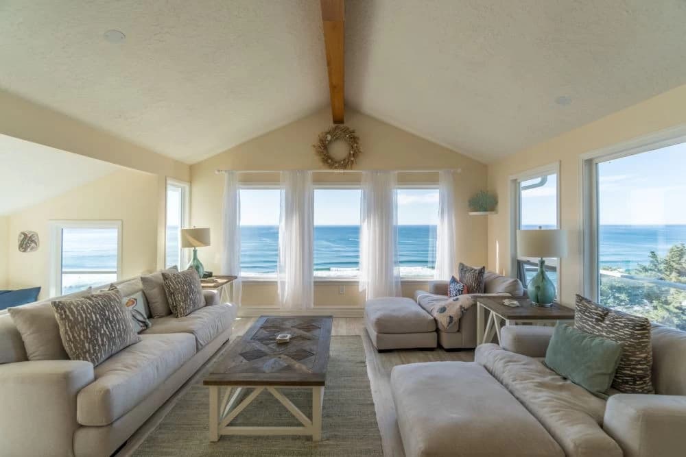 Bright living room in Neskowin with beige sofas, wood table, and ocean view windows