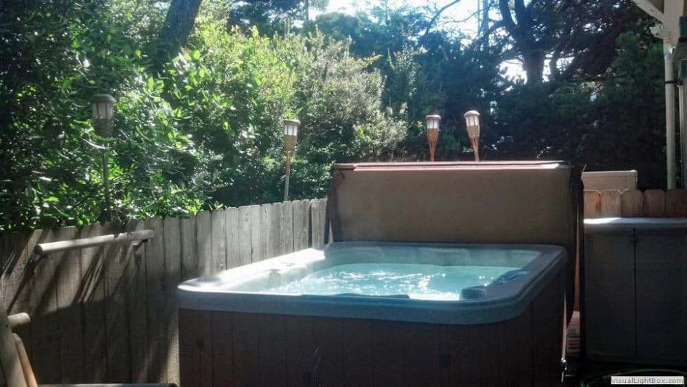 Wood-paneled hot tub on a deck in Florence, with bubbling water and a privacy fence