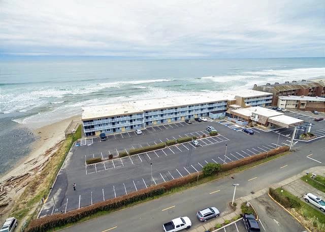 Aerial view of a tan oceanfront building in Lincoln City with blue balconies and beach