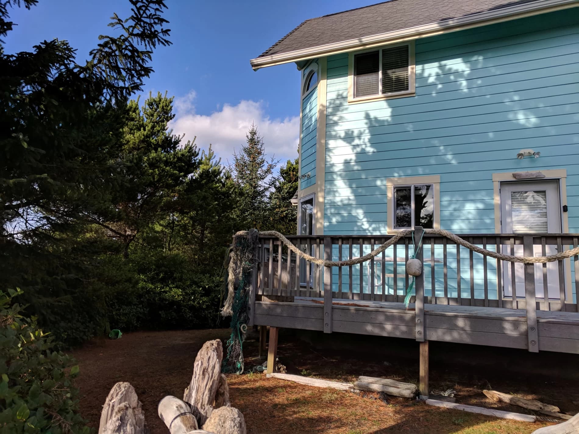 Light-blue house in Florence with a wood deck, nautical rope railing, and driftwood