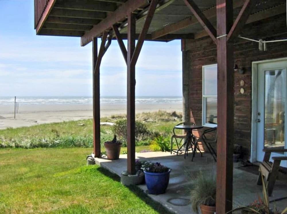 Covered patio in Moclips with bistro chairs and a blue planter facing beach and ocean