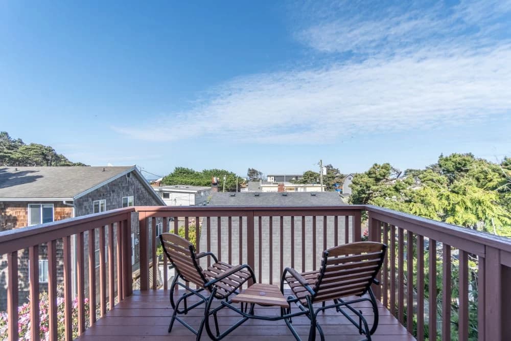 Wood rocking chairs on a stained deck in Lincoln City overlooking neighborhood rooftops