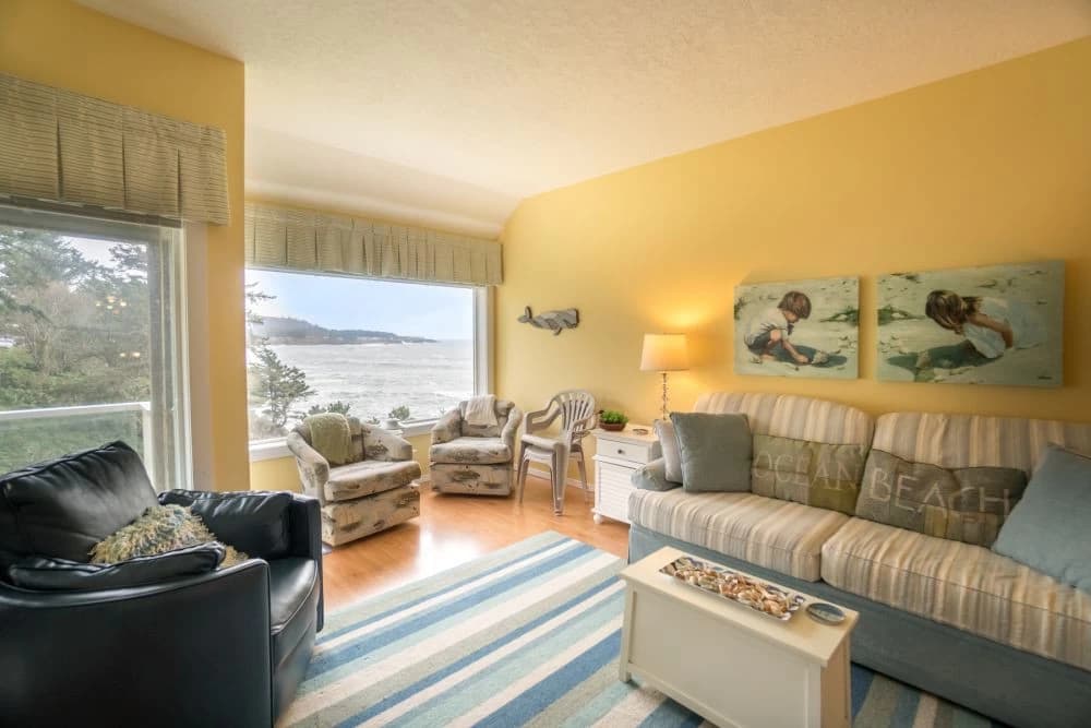Yellow living room in Depoe Bay with a striped sofa and ocean view through large windows
