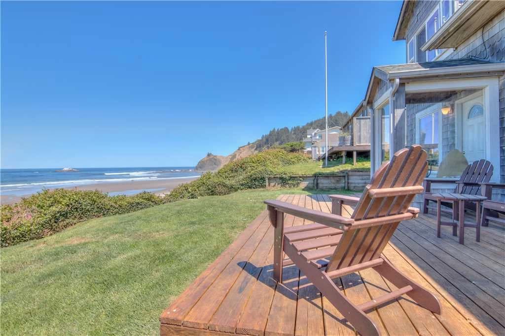Wooden deck and Adirondack chair in Lincoln City facing lawn, beach, and ocean headland