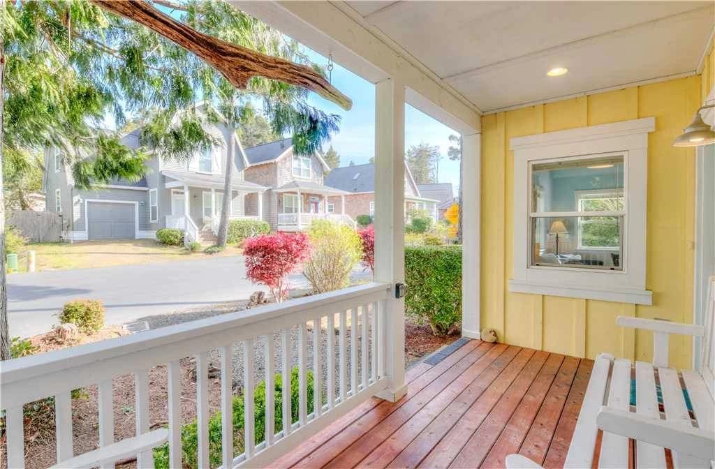 Yellow house porch in Depoe Bay with a white railing looking over a quiet neighborhood street
