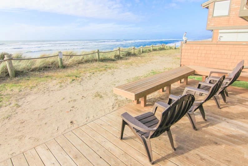 Brown Adirondack chairs and wooden bench on a deck facing ocean in Neskowin