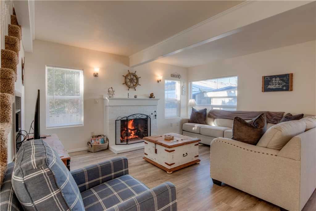 White fireplace with ship's wheel, plaid chair, and cream sofa in Seaside