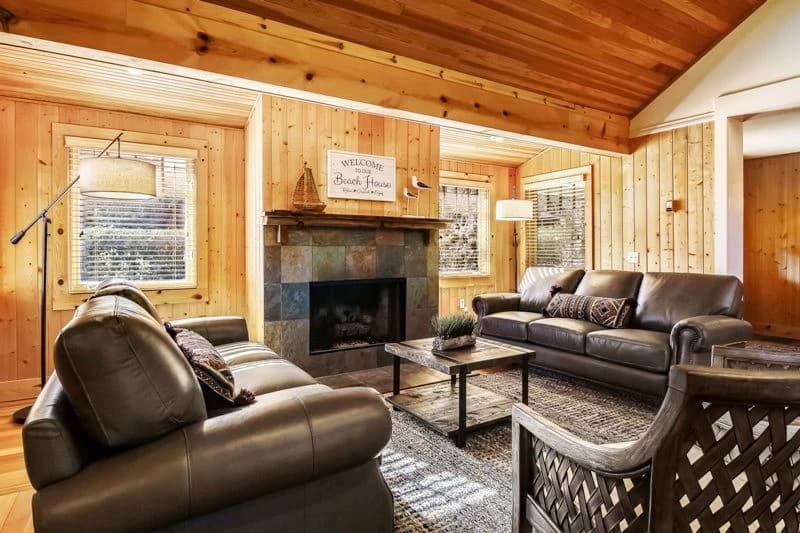 Wood-paneled Cannon Beach living room with leather sofas and a slate-tile fireplace