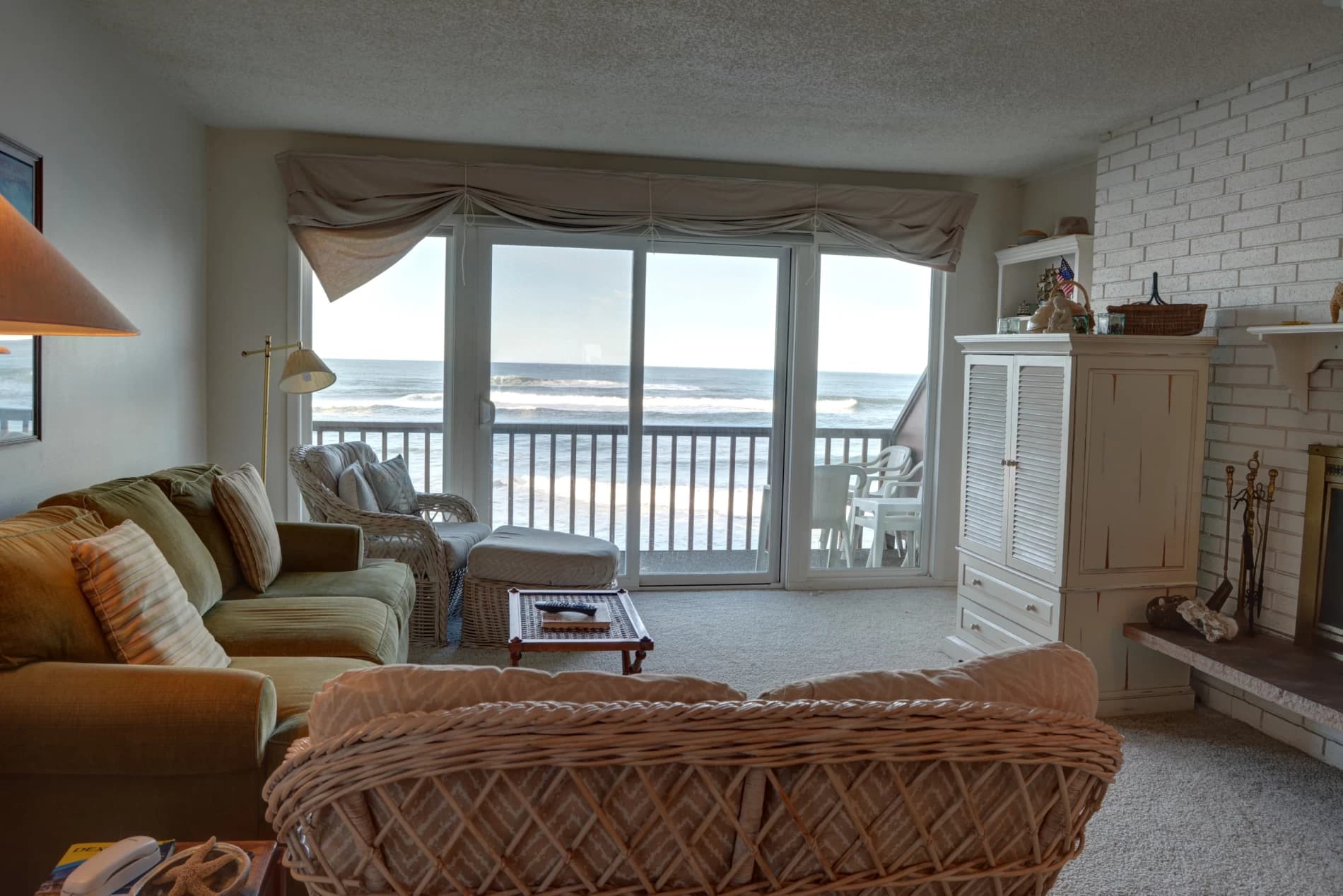 Neskowin living room with a green sofa, wicker armchair, and sliding doors to an ocean-view deck