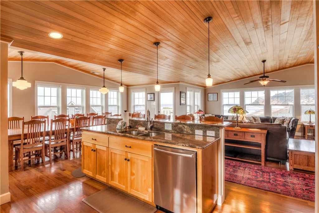 Lincoln City great room with a vaulted wood ceiling, granite island, long dining table, and beach windows