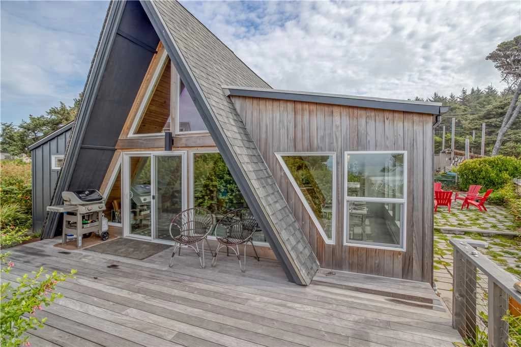 A-frame South Beach house with a wood deck, grill, and red Adirondack chairs