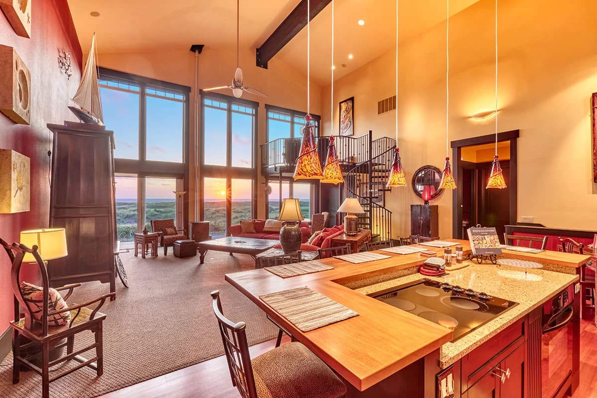 Ocean Park great room with glowing pendants, red sofas, and sunset ocean windows