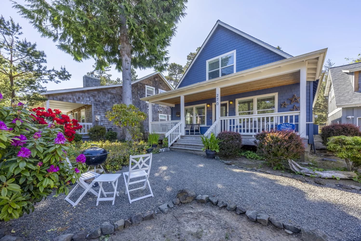 Blue two-story house in Lincoln Beach with a white porch, gravel patio, and kettle grill