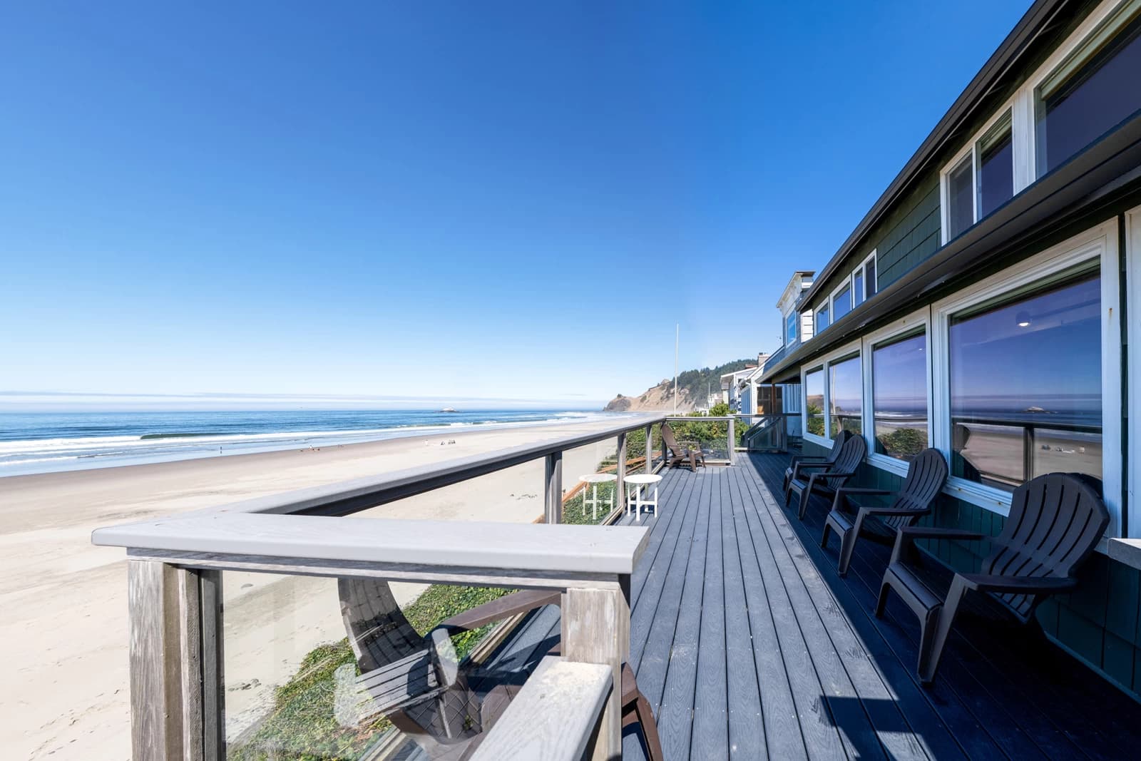 Lincoln City oceanfront deck with gray Adirondack chairs, glass railing, and sandy beach