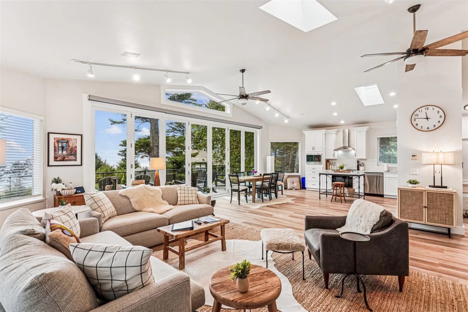Vaulted Arch Cape living room with tan sofas, a dining table, and kitchen beyond