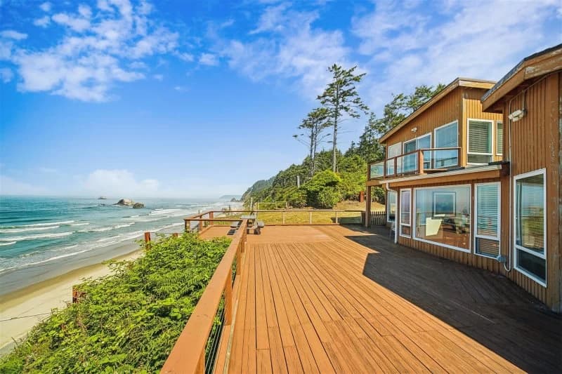 Tan Arch Cape house with a large wood deck, picnic table, and oceanfront beach view