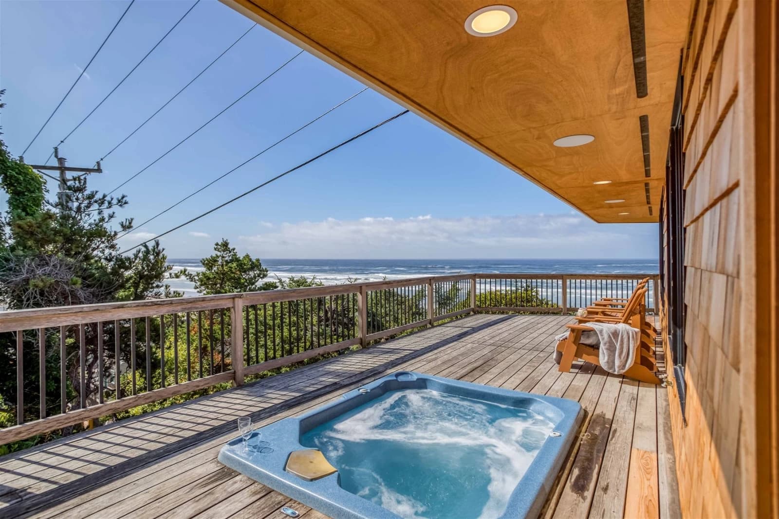 Cannon Beach deck with a built-in blue hot tub, Adirondack chairs, and an ocean view