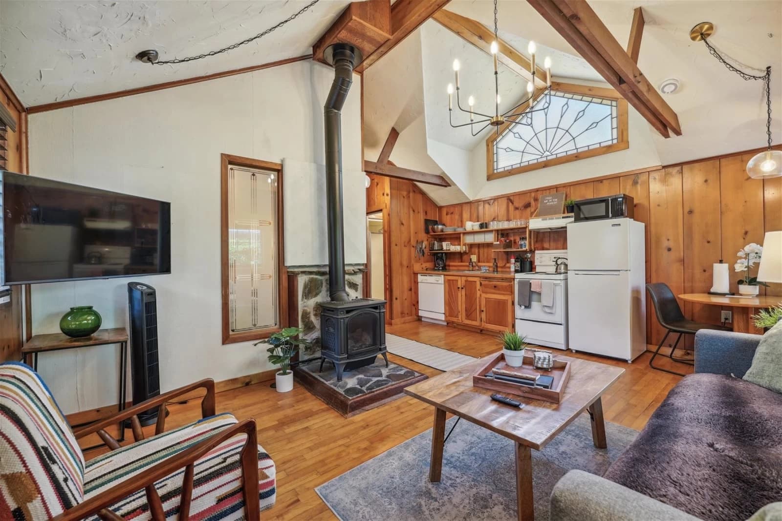 Cabin living room in Cannon Beach with a wood stove, vaulted beams, and open kitchen