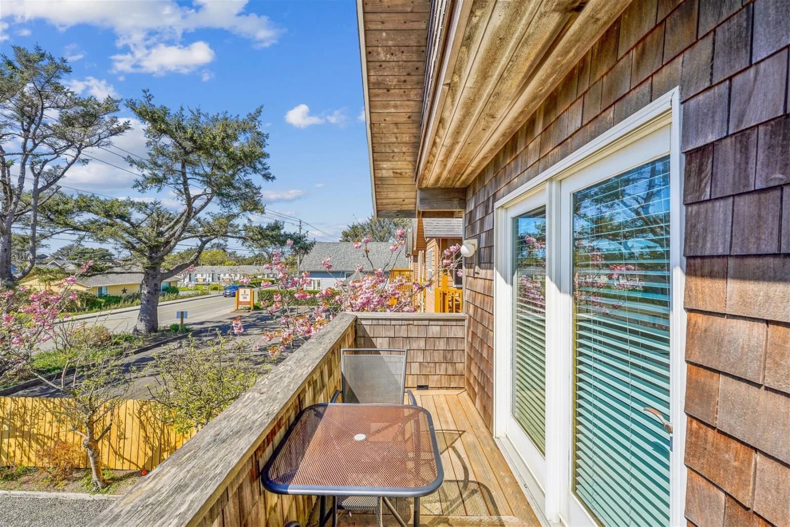 Cedar-shingle balcony in Cannon Beach with a glass table and grey mesh chair