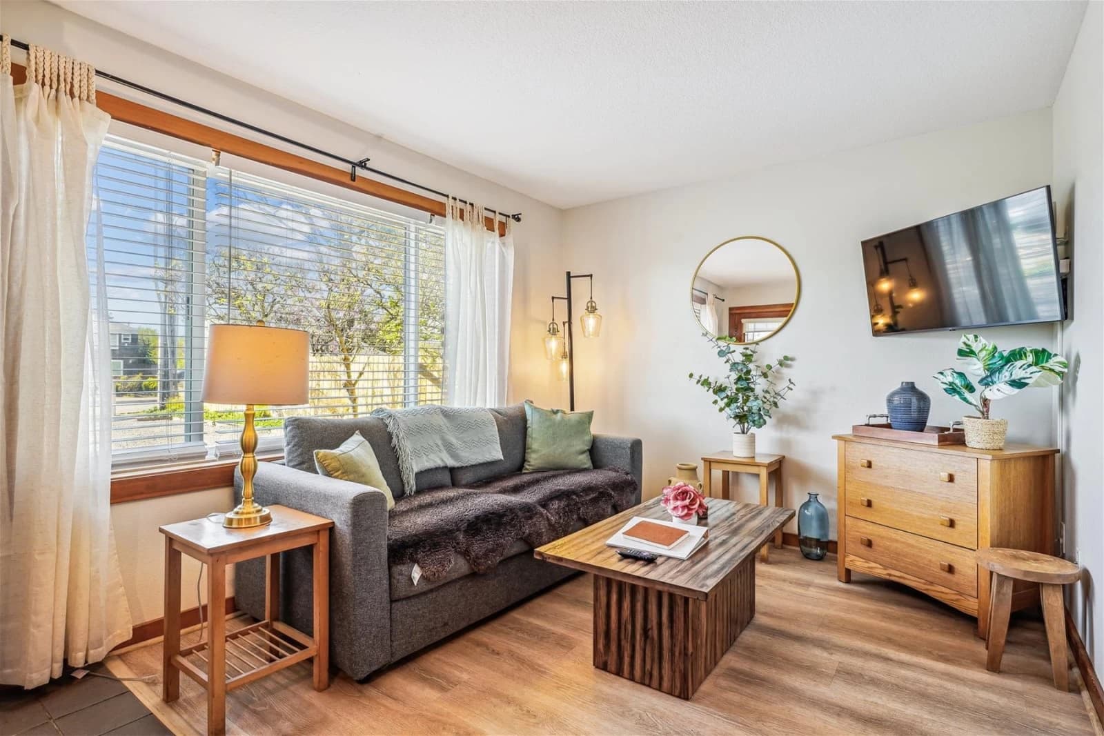 Living room in Cannon Beach with a gray sofa, wood coffee table, and window to trees