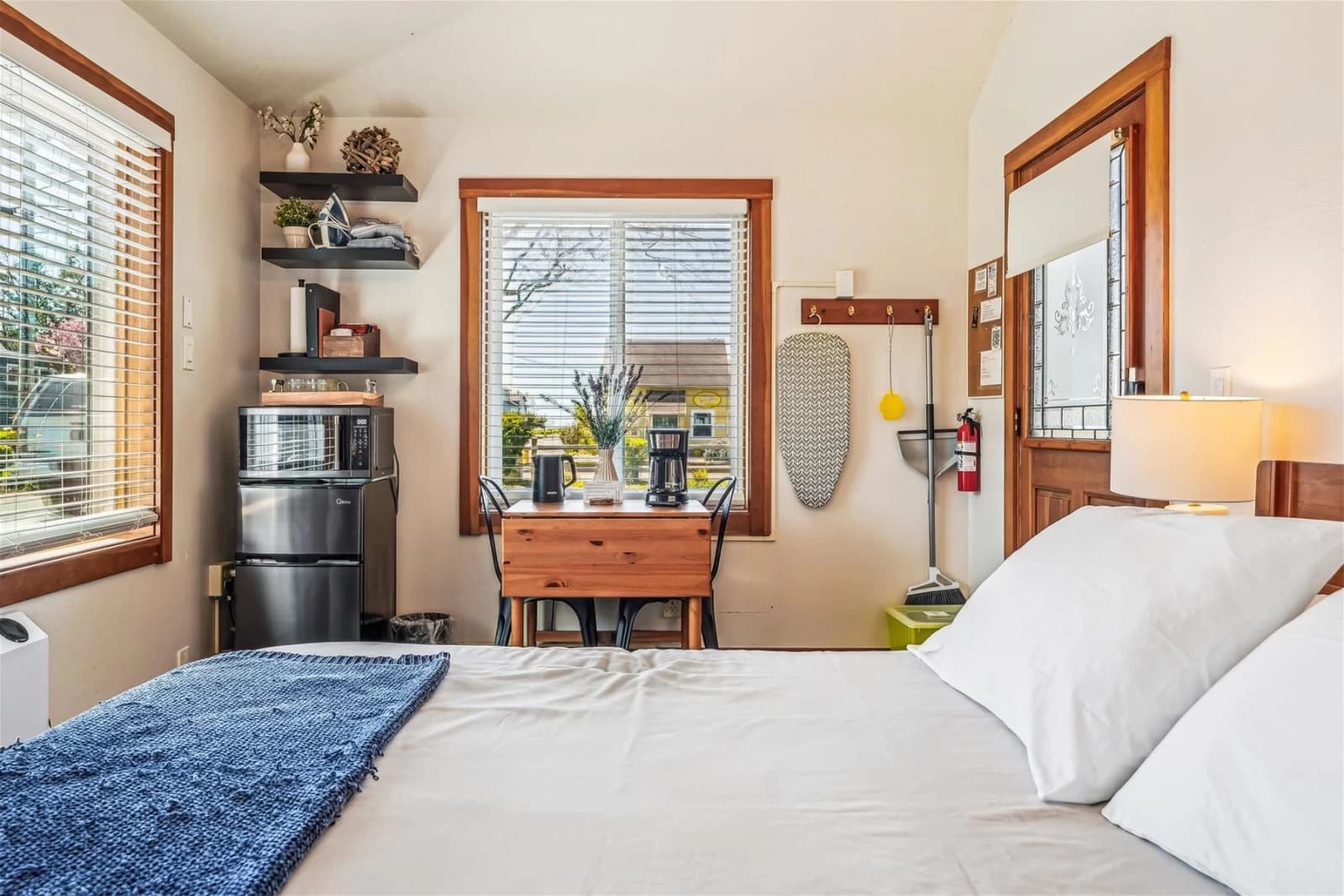 Studio in Cannon Beach with a made bed, blue throw, wood table, and mini-fridge