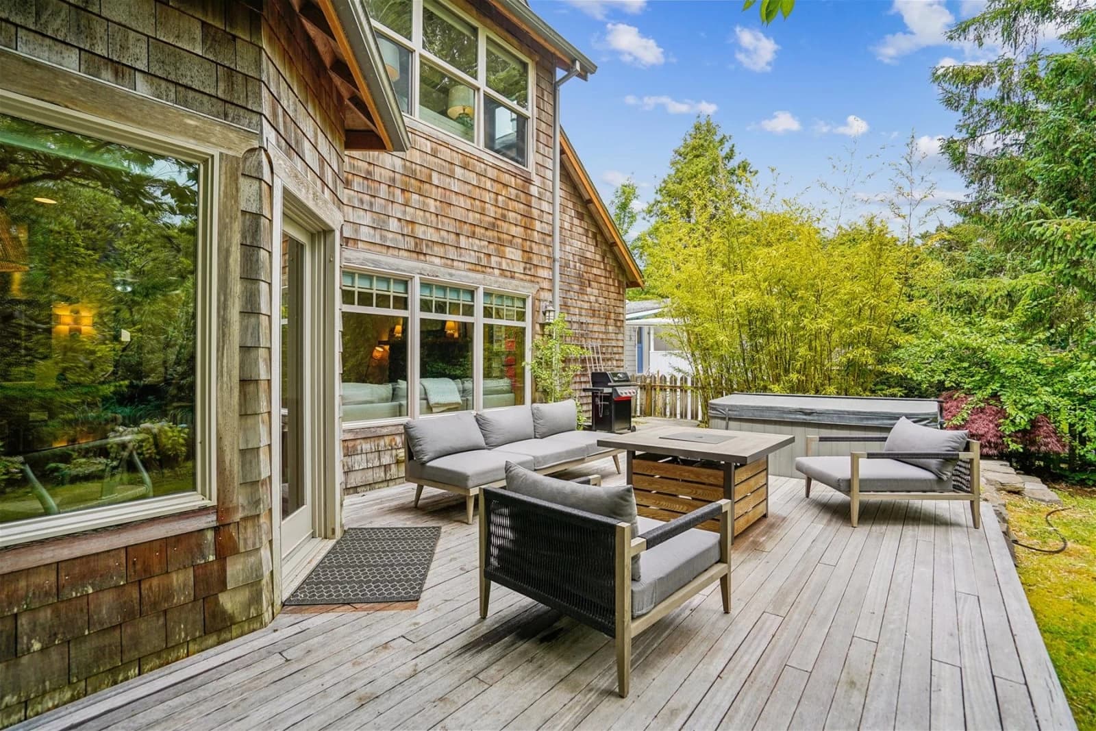 Cedar-shingle deck in Cannon Beach with grey patio furniture, fire pit, and hot tub