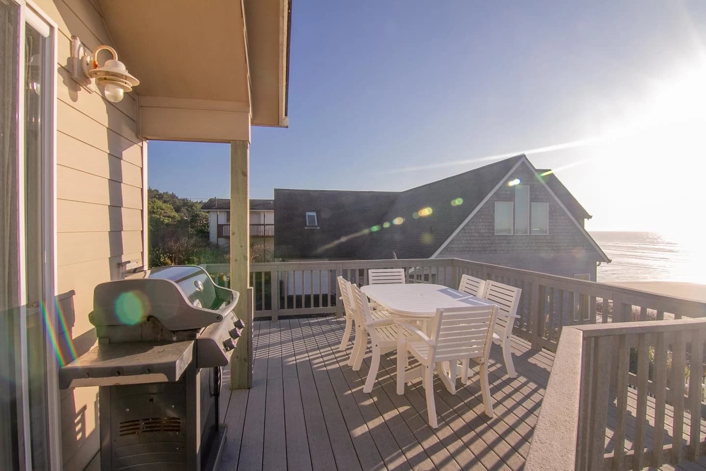 Gray deck in South Beach with a white dining set, gas grill, and ocean view beyond