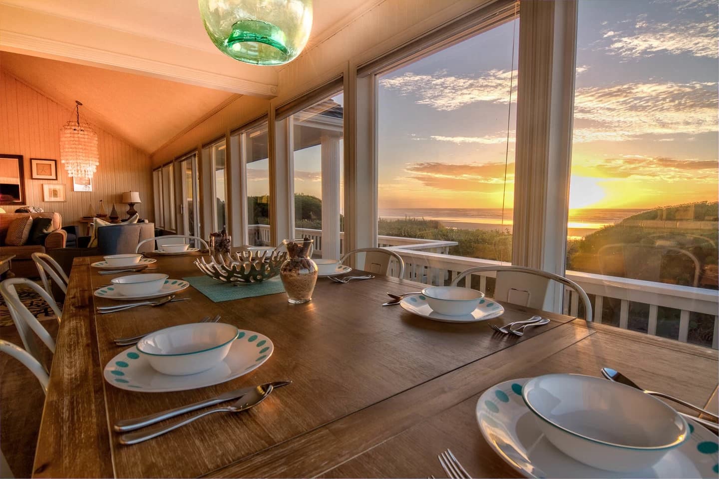 Waldport dining table by windows looking onto a sunset over the beach and ocean
