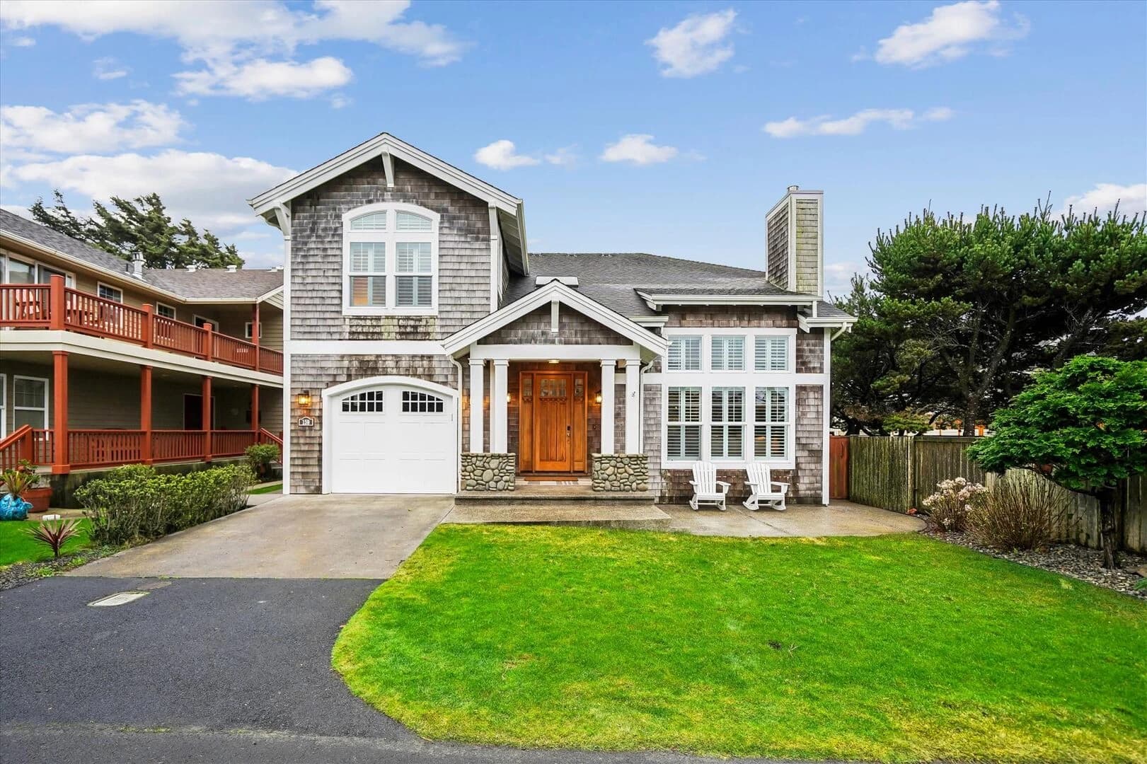 Gray cedar-shake house in Cannon Beach with a white garage and two Adirondack chairs