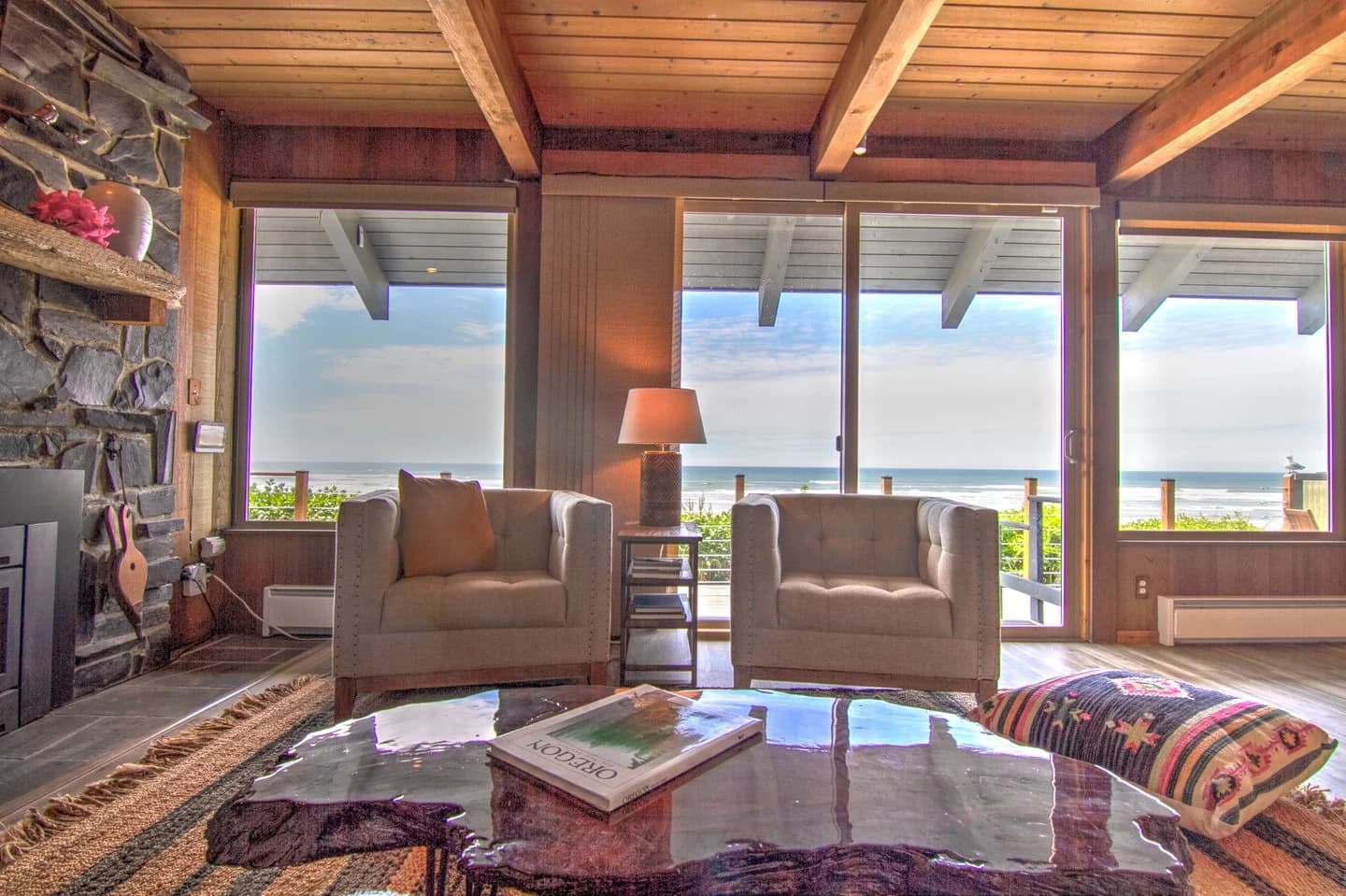 Living room in Yachats with tufted chairs, a live-edge table, and ocean-view windows