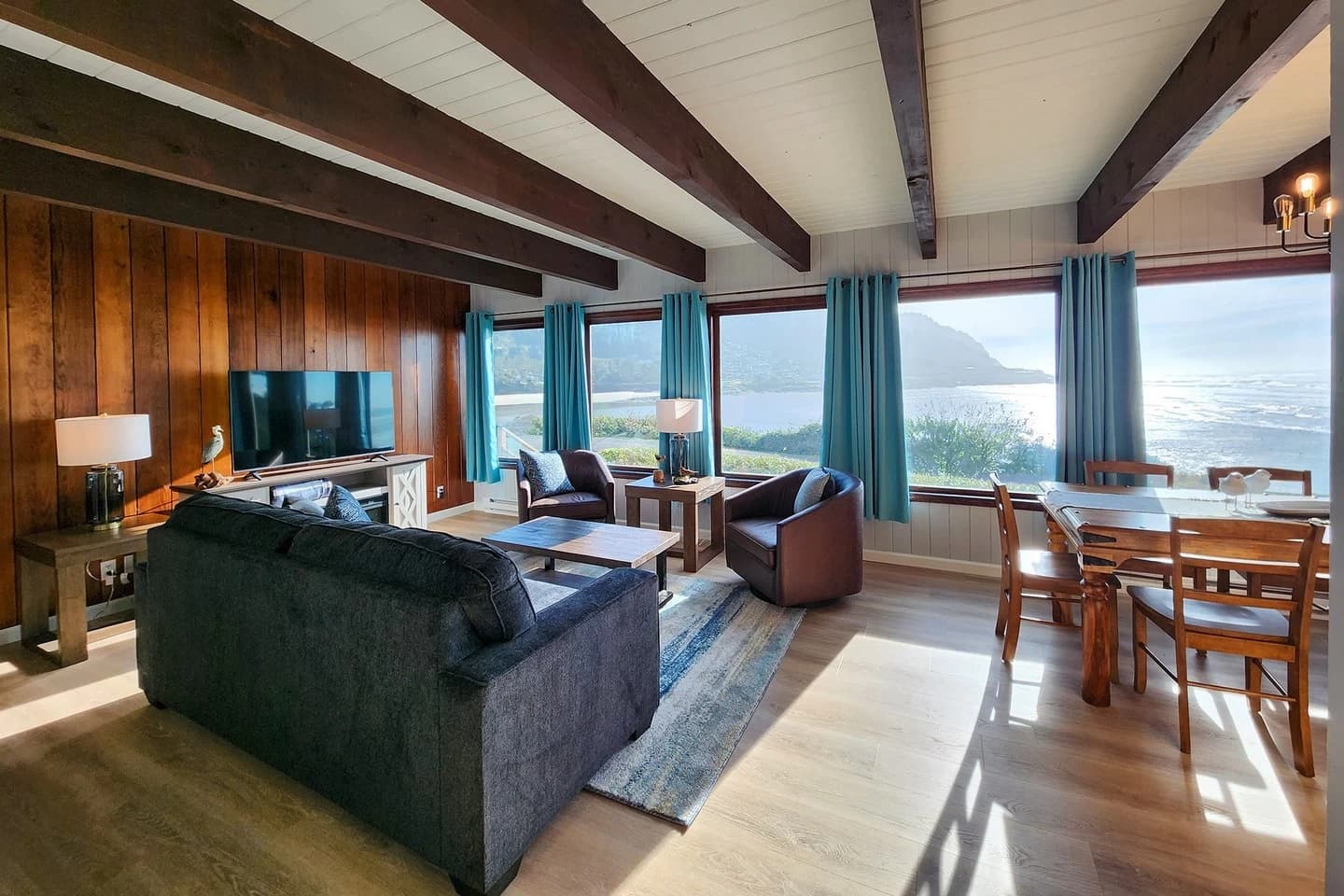Beamed living room in Yachats with a charcoal sofa, leather chairs, and ocean windows