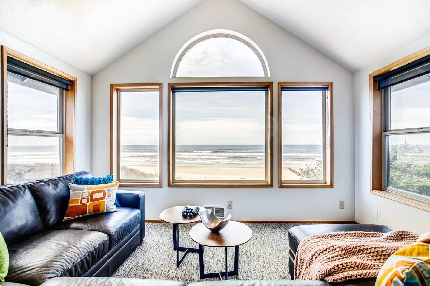 Yachats living room with a dark leather sofa and arched windows facing the ocean