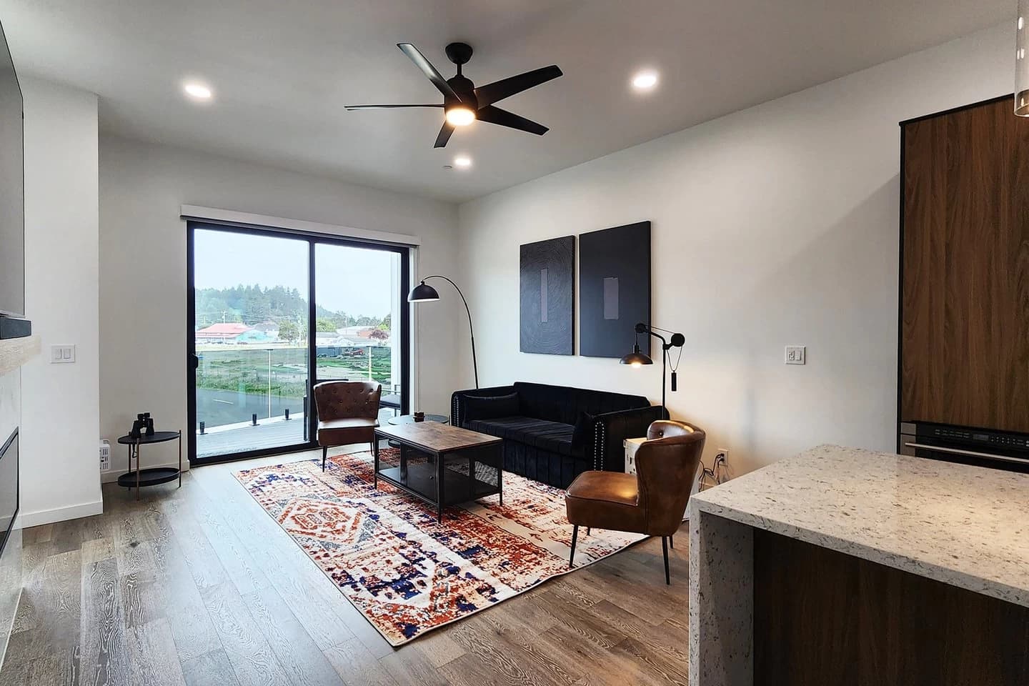 Waldport living room with a black sofa, leather chairs, and a bay-view balcony