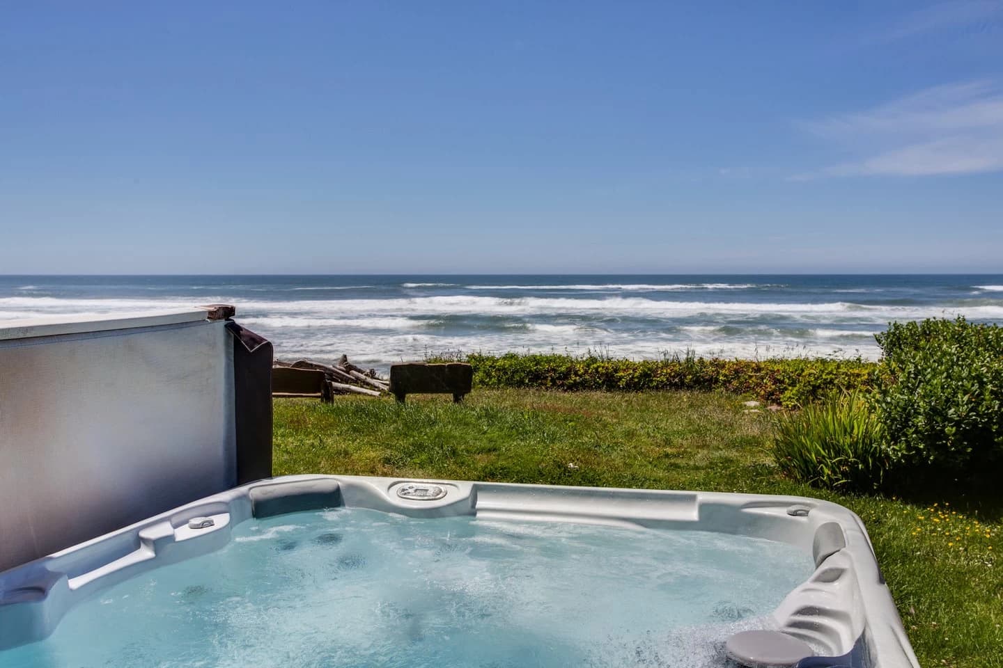 White hot tub on a grassy Yachats lawn facing the ocean and breaking waves
