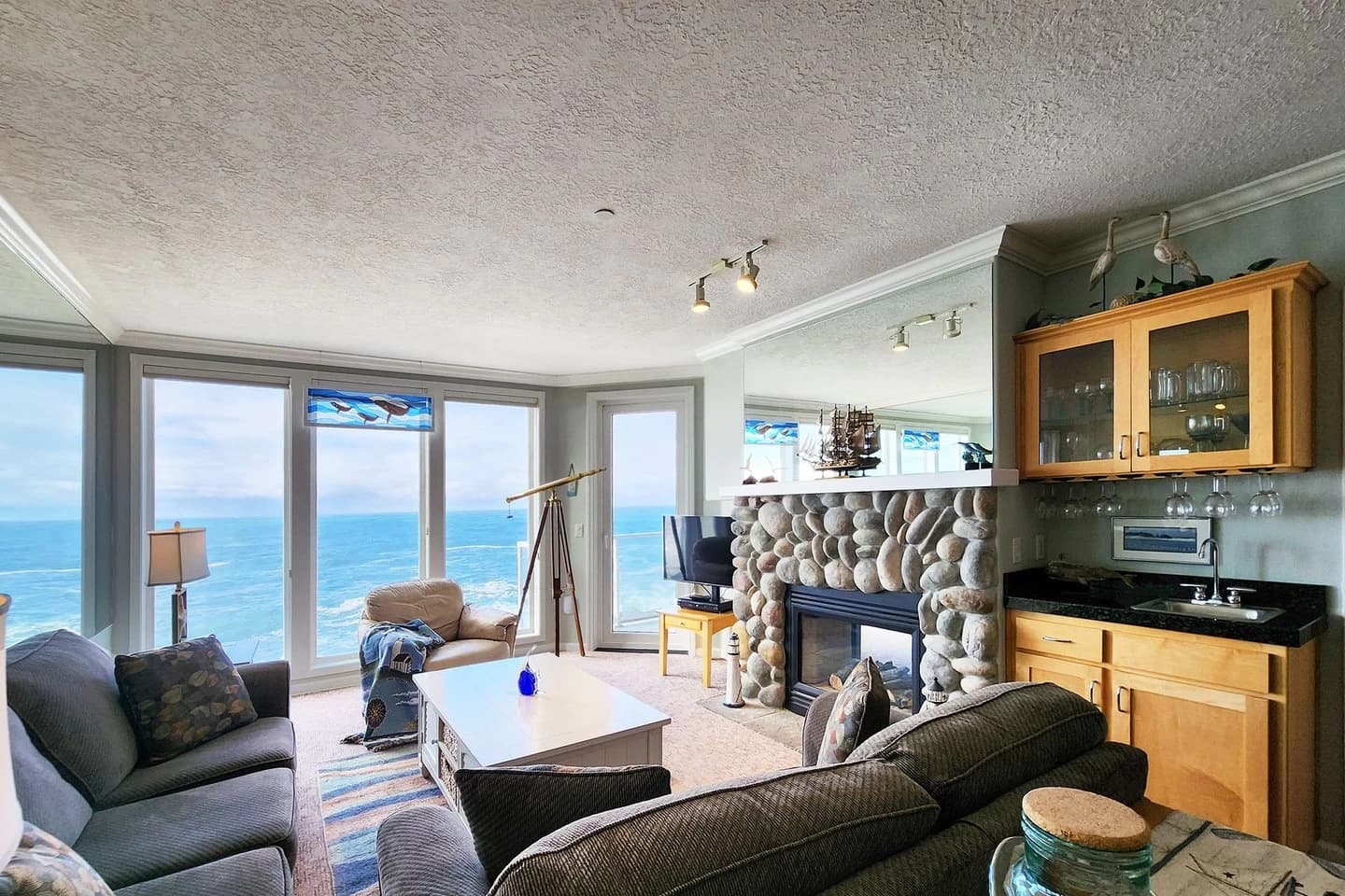 Depoe Bay living room with a river-stone fireplace, telescope, and ocean windows