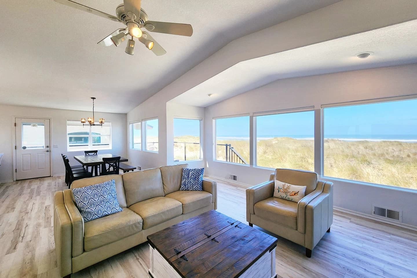 Tan leather sofa and armchair face dune and ocean windows in a Waldport living room