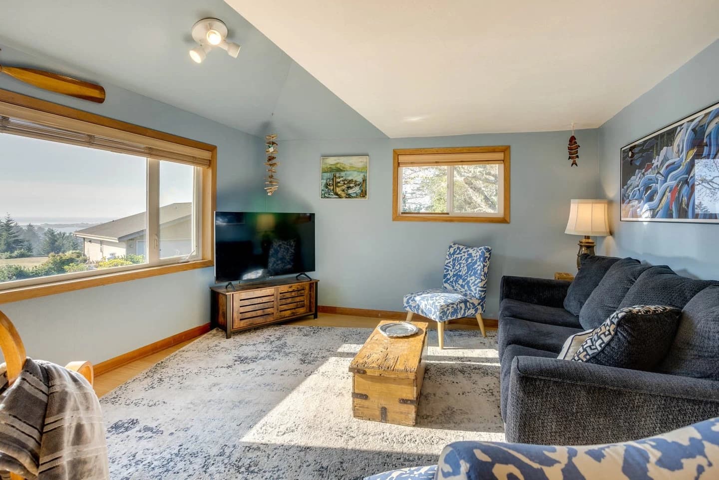 Navy sofa, floral armchair, and wood trunk table in a light-blue Waldport living room