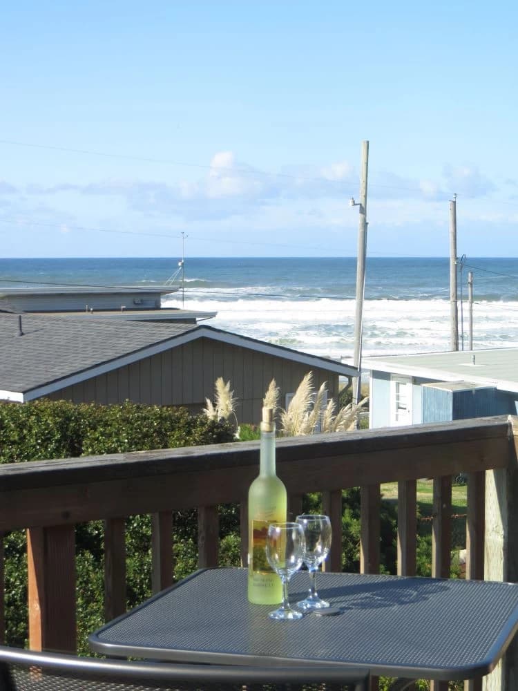 Deck in Florence with a wine bottle, neighboring rooftops, and ocean waves beyond