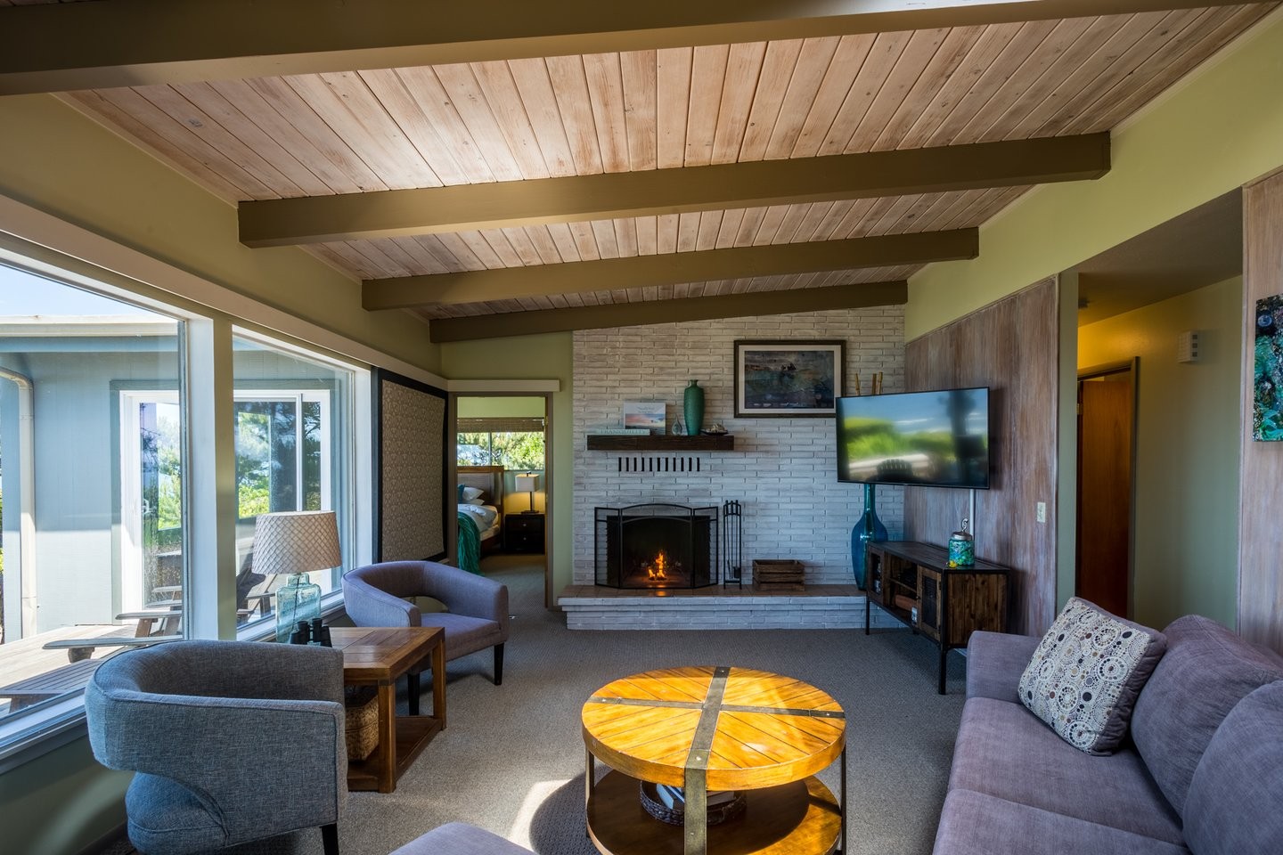 Oceanfront living room at Tranquility Rocks in Seal Rock, OR with floor-to-ceiling windows and fireplace overlooking the Pacific Ocean.