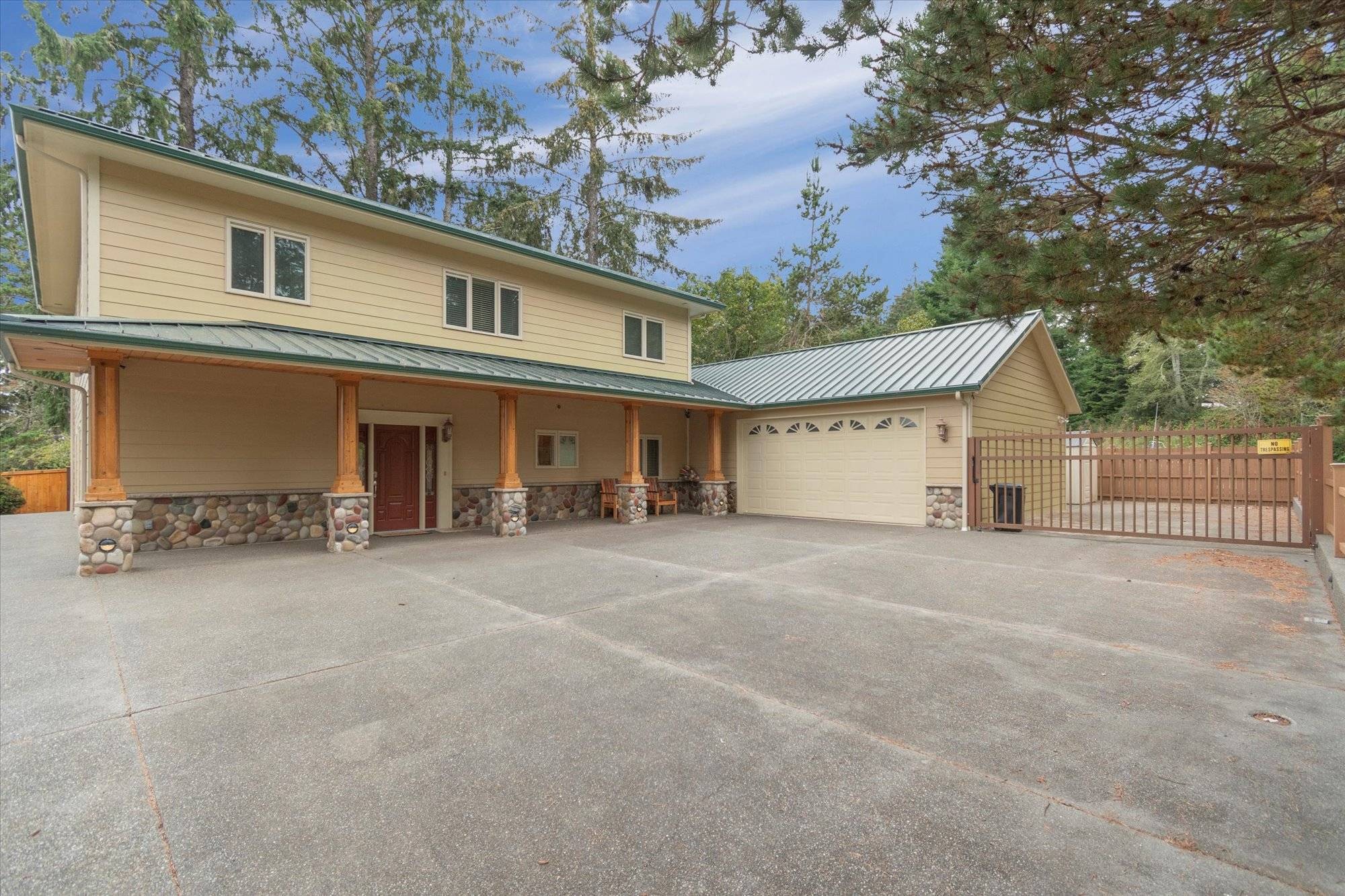 Exterior view large vacation home with garage and huge paved parking area with gate.
