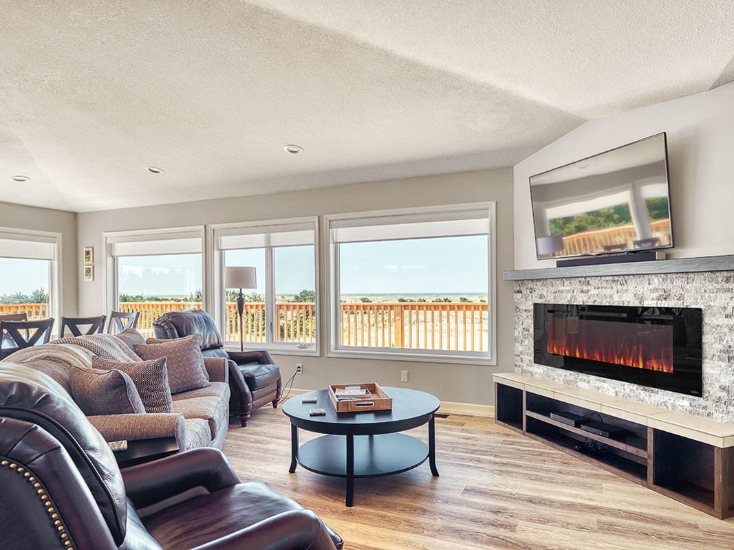 Beautiful views of low lying grassy dunes and blue sky from the deck of a beachfront rental.